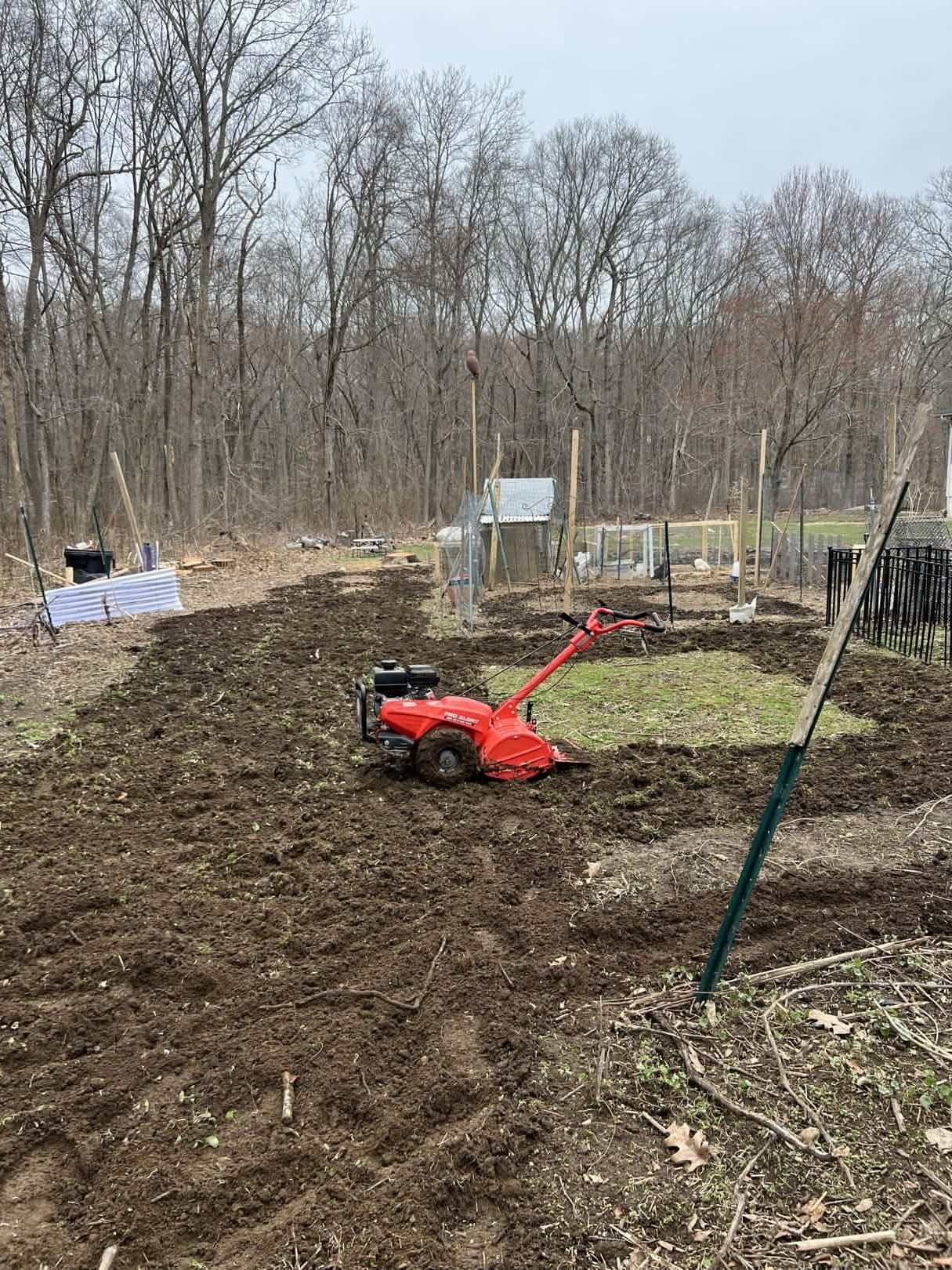 Tilling the main garden plot behind the coop — the chickens follow the tractor row by row.